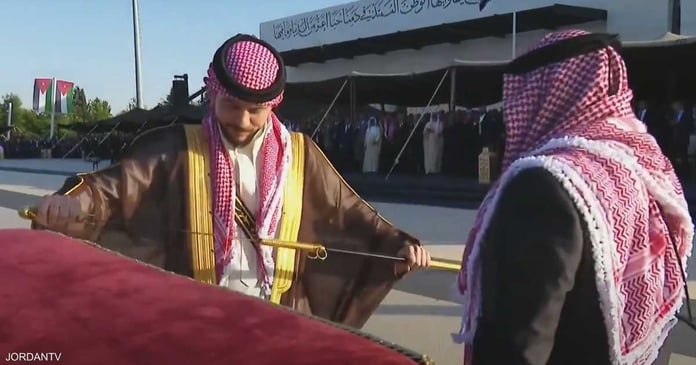 The Jordanian monarch presents the crown prince with a Hashemite sword.

