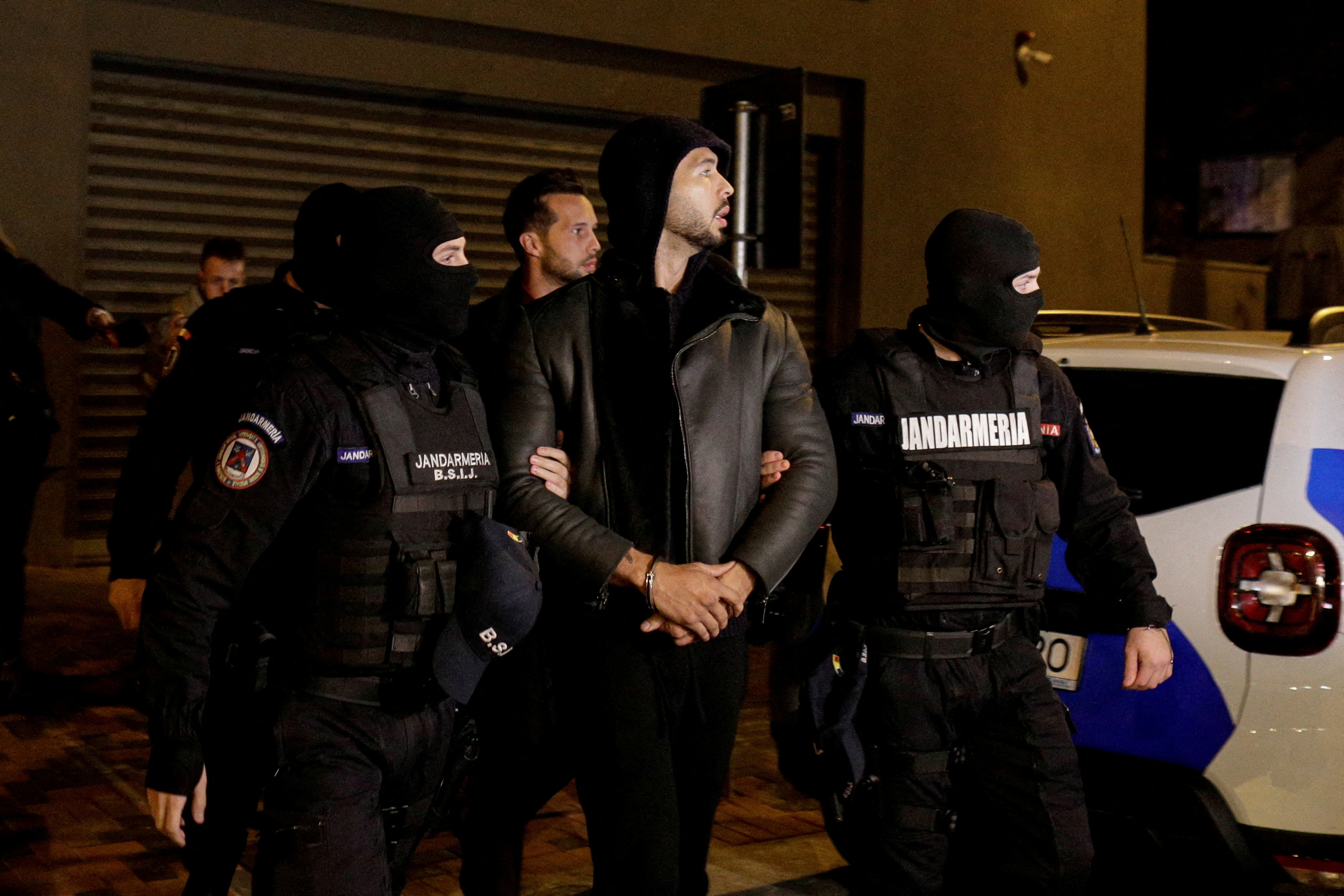 Andrew Tate and Tristan Tate being escorted by law enforcement officials outside the DIICOT headquarters in Bucharest, Romania, after a 24-hour detention