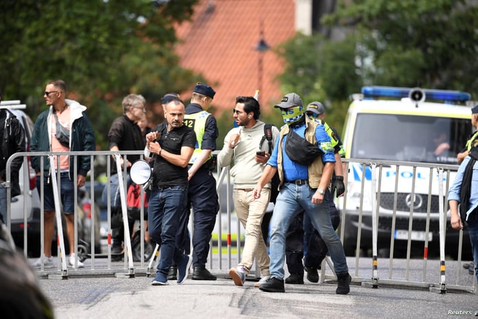 Salwan Momika is escorted by police to a location outside the Iraqi embassy, in Stockholm
